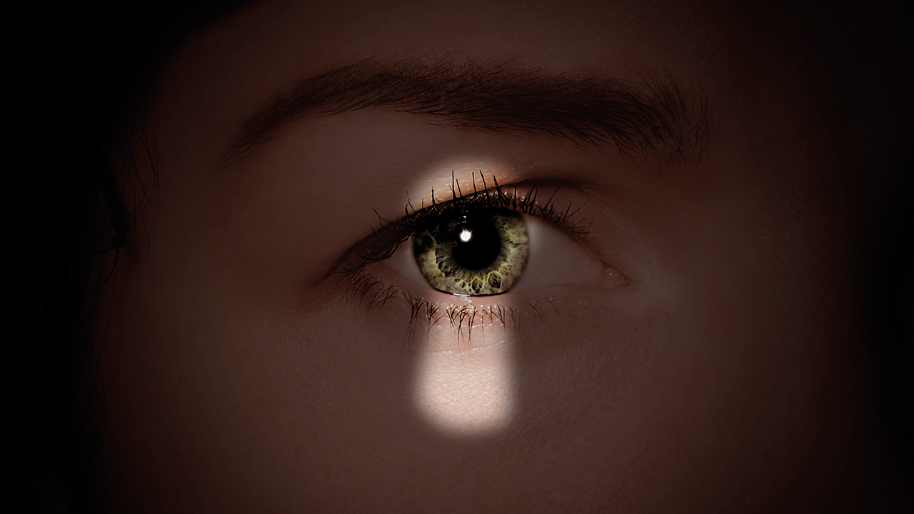Närbild på öga som lyser upp av ett nyckelhålsformat ljus