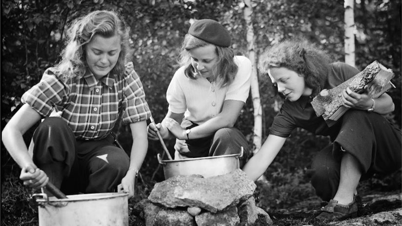 Svartvitt foto av tre kvinnor som lagar mat utomhus